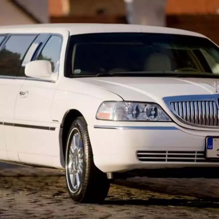 White Lincoln limousine parked outside of a building waiting for a bachelor party group to get on board.