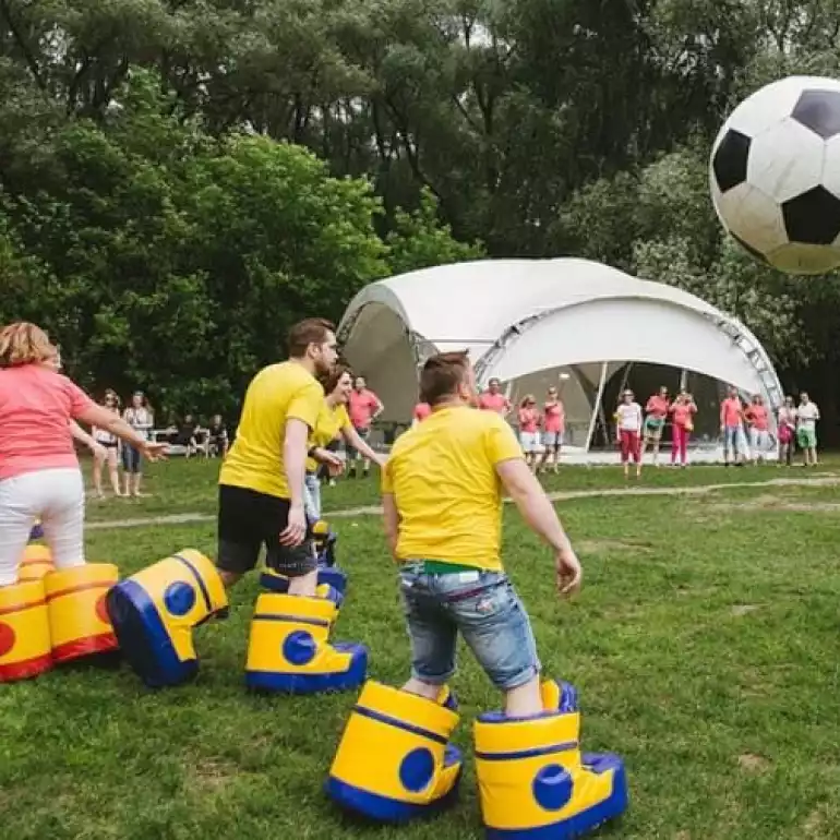 People playing bubble football outdoors in inflatable bubbles.