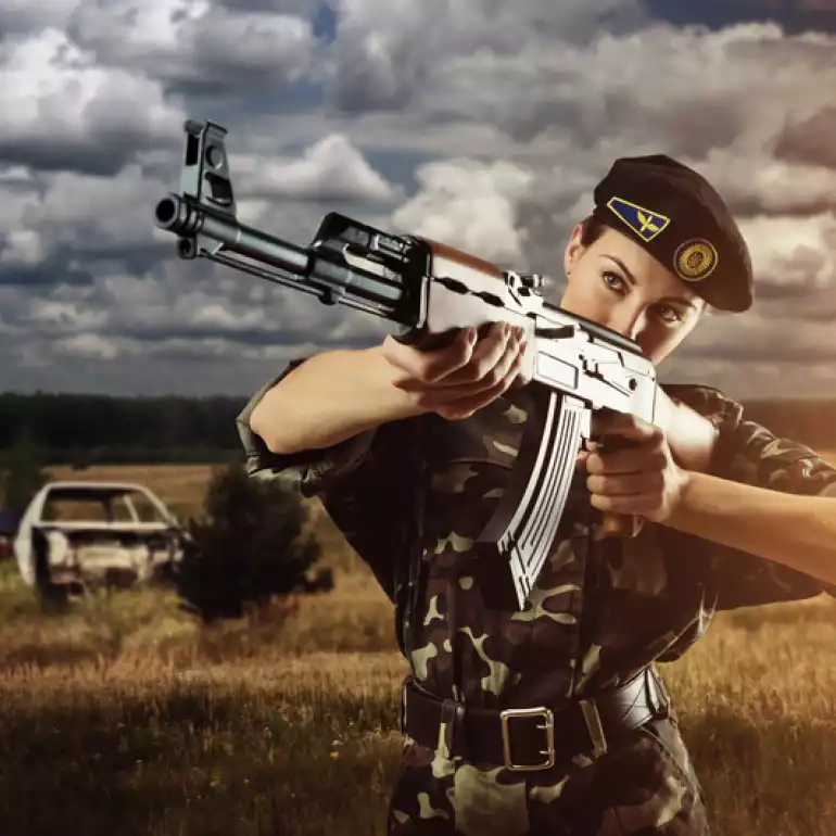 Lady dressed in a uniform shooting at an outdoor gun range.