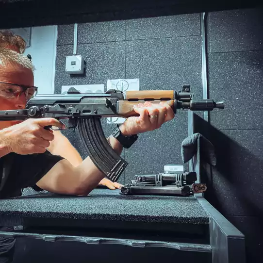 Professional instructor with safety gear shooting from a riffle at a gun range in Budapest.