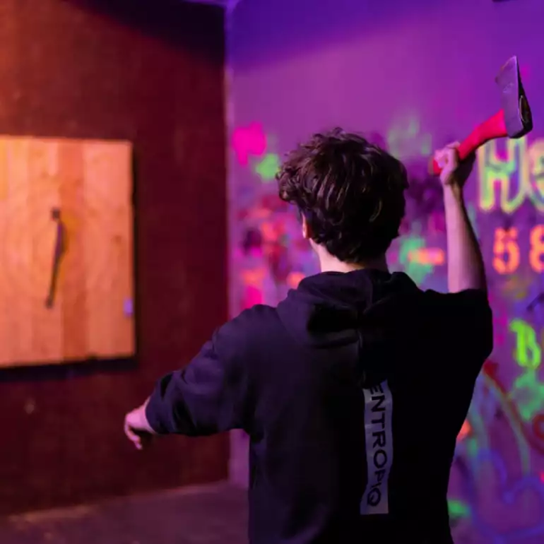 A person in black shirt enjoying an axe throwing experience in Budapest.