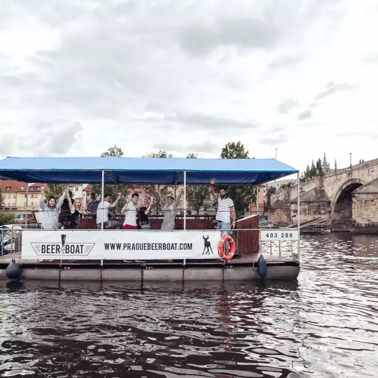 Prague party boat floating by a bridge on Vltava river.