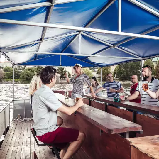 Group of people enjoying beer on a party boat on Vltava river.