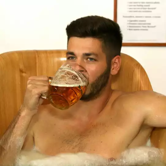 Man enjoying a glass of Czech beer in a beer bath.