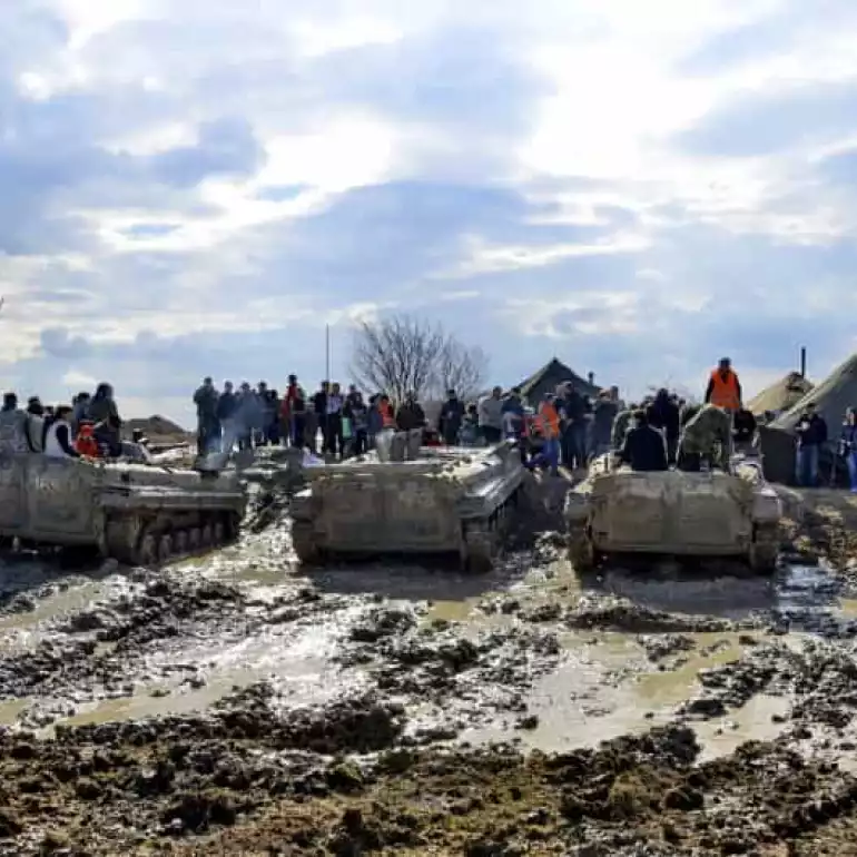 Multiple tanks parked at a field.