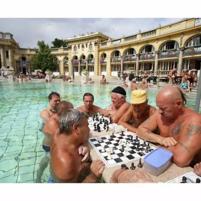 Group of guys playing chess while enjoying the gem of Budapest - Széchenyi Spa.