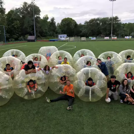 Large group of people after playing bubble football posing in zorb balls.