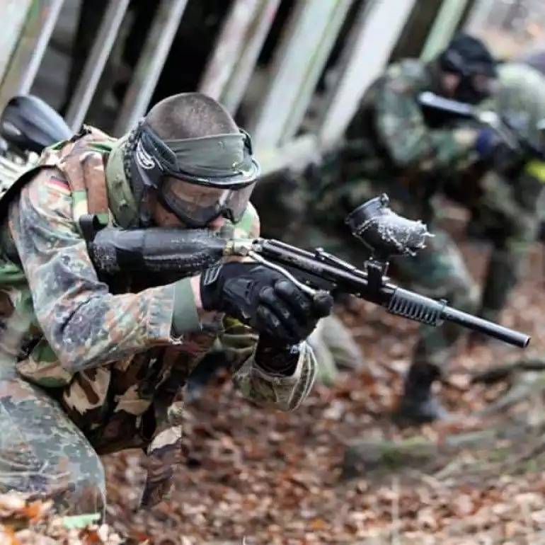 Group of paintball players in full gear on an outdoor field waiting for a game to start.