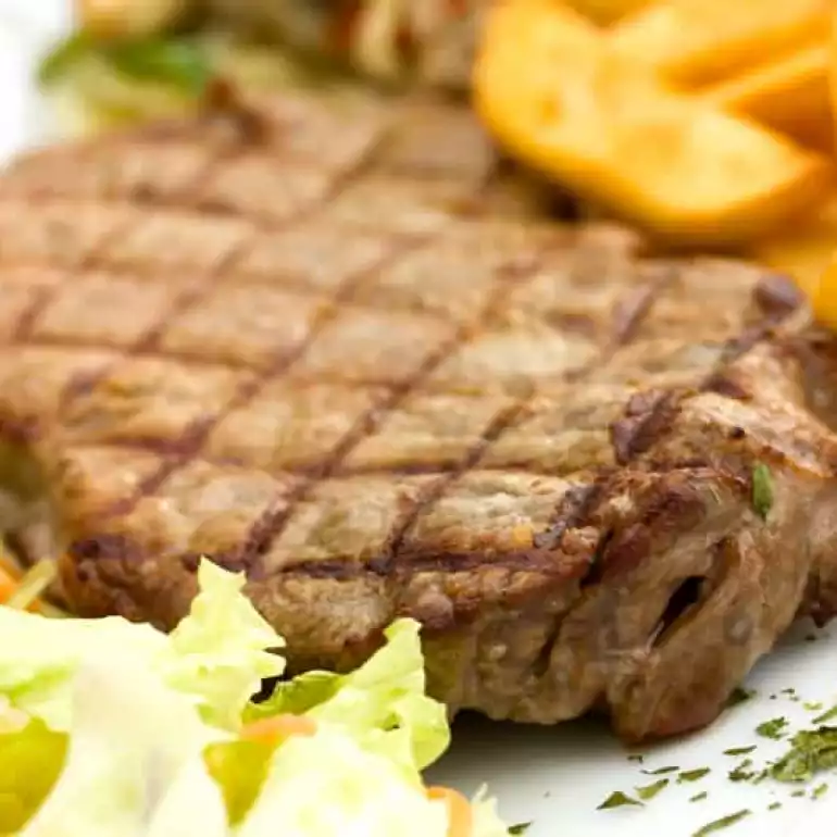 Well cooked steak with potatoes wedges and salad.